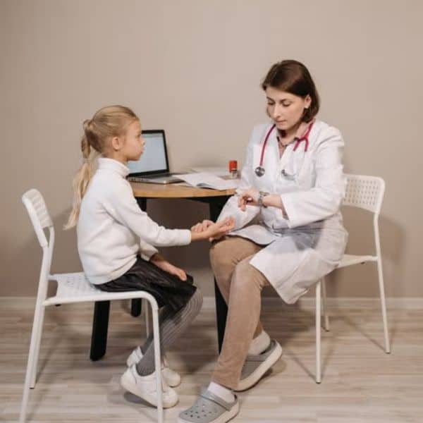 Médica realizando exame em criança em consultório pediátrico.